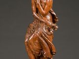 une statue en bois représentant une femme assise sur une table