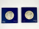 deux pièces d'argent dans une boîte bleue posée sur une surface blanche
