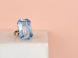 a close up of a blue topaz ring on a white pedestal