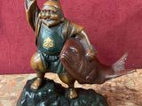 une figurine représentant un homme tenant un poisson sur un rocher