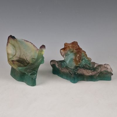 deux figurines représentant une femme assise sur un rocher, un poisson à la main