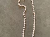 a white pearl necklace with a gold clasp