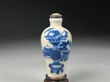 blue and white porcelain vase with a wooden stand on a gray surface