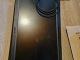 une tablette posée sur une table, avec un chargeur dessus
