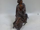 bronze statue of a woman sitting on a chair with a dog
