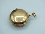 a small gold pocket watch on a white surface