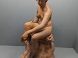 l'image d'une statue de femme assise sur un rocher