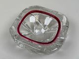 a glass ashtray with a red rim on a white table
