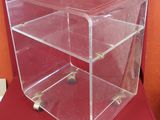 clear acrylic display case with three shelves on a red chair