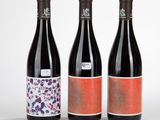trois bouteilles de vin ornées de motifs différents sur fond blanc