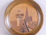 une assiette en bois sur laquelle est représenté un bâtiment