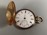 une montre de poche en or posée sur une surface blanche