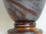 a black vase with a brown base sitting on a table