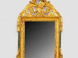 un miroir avec un cadre doré sur un mur blanc