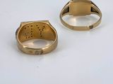 two gold rings on a white surface, one with a hole in the middle
