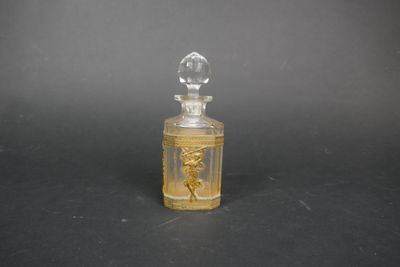 une image représentant une petite bouteille en verre ornée d'un motif doré