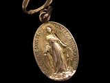 an image of a gold medal with the image of the virgin of guadalupe on it