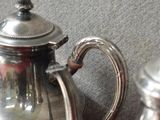 une théière en argent et une théière en argent posées sur une table rouge