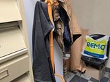 a coat rack in the corner of a room with clothes on it