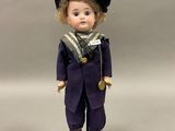 une figurine représentant un garçon vêtu d'un costume de marin et d'une casquette
