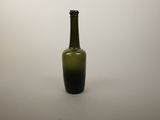 a green glass bottle sitting on a white surface