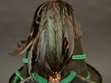 a green hat with feathers on top of a glass stand