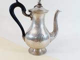 a silver tea pot with a black handle on a table