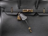 a black leather handbag with a lock on it