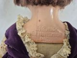 a close up of a doll wearing a purple dress