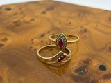 pair of gold rings with garnetts on top of a piece of wood