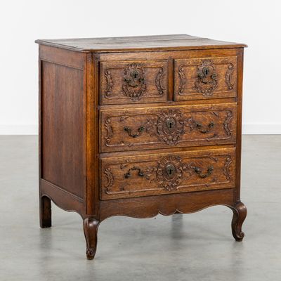 une vieille commode en bois dont les tiroirs sont ornés de sculptures
