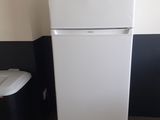 un réfrigérateur blanc à côté d'une poubelle dans une pièce