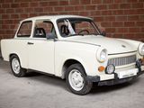a small white car that is parked in front of a brick wall