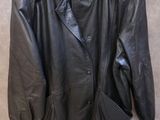 une veste en cuir noir suspendue à un cintre accroché au mur
