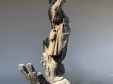 a statue of a man holding a bird on top of a piece of wood