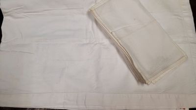 a piece of white cloth on the table next to a folded napkin