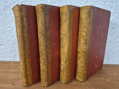 three old books sitting on top of a wooden table next to each other