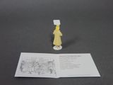 a small figurine of a woman in a yellow dress next to an open book