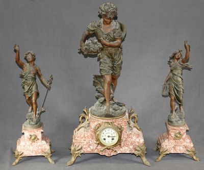 trois statues représentant une femme et un homme sur une horloge