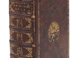un vieux livre marron orné d'inscriptions dorées, posé sur une surface blanche