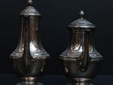 pair of antique silverplated salt and pepper shakers on a black background