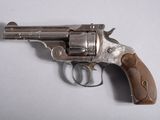 un vieux revolver avec une poignée en bois sur une surface blanche