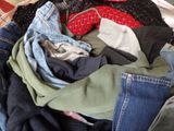 a pile of clothes that is sitting on a bed