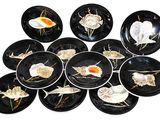 many black plates with shells on them on a white surface