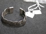 silver bracelet with braid design on a black surface with a tag on it