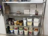 une étagère métallique sur laquelle sont posés des seaux remplis de nourriture