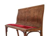 a wooden bench with a red cushion on it