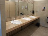 deux lavabos dans des toilettes publiques, avec un distributeur de serviettes en papier fixé au mur