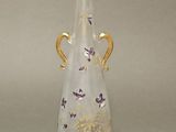 a glass vase with a gold handle on a table
