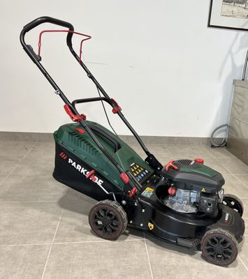 une tondeuse à gazon verte et noire posée sur le carrelage d'une pièce